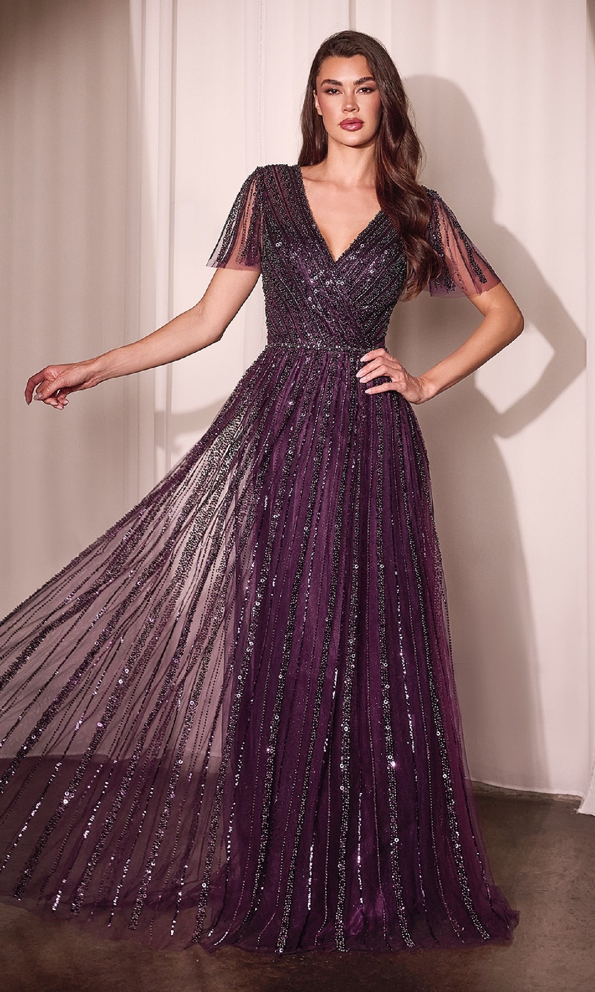A woman wears the Ladivine CD0241 Flutter-Sleeve Long Prom Dress in deep purple, featuring short flutter sleeves, a V-neckline, vertical sequin stripes—ideal as an elegant evening gown for special occasions.